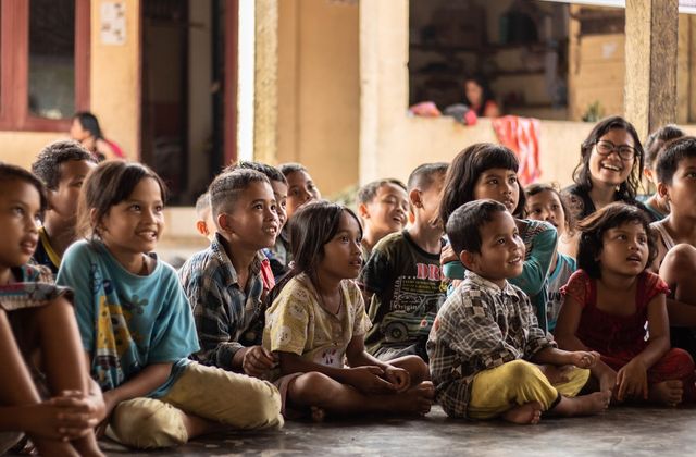 A large group of children sitting on the floor, smiling and looking up
